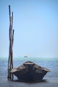 Wooden posts in sea against clear sky