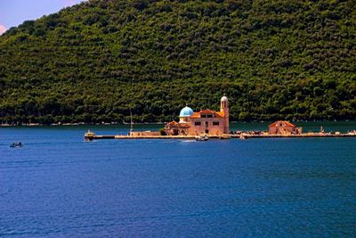 Scenic view of sea and buildings against trees