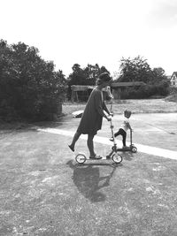 Mother and daughter riding push scooter on road