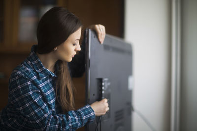 Young woman checking tv at home