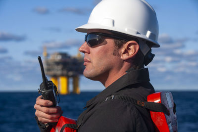 Portrait of man holding sunglasses in sea