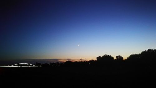 Silhouette trees against clear sky at night