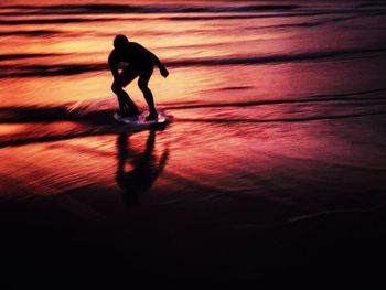 Silhouette man walking on beach during sunset