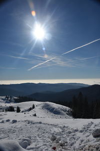 Scenic view of snow covered landscape against bright sun