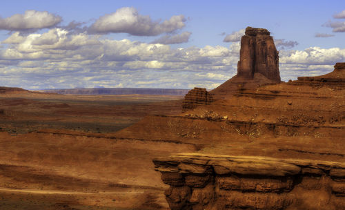 Rock formations on landscape against cloudy sky