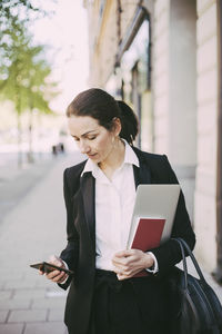 Businesswoman using smart phone in city