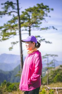 Young woman standing on field against sky