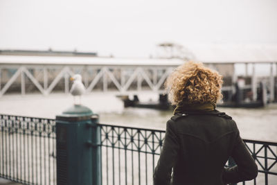 Rear view of woman standing against railing in city