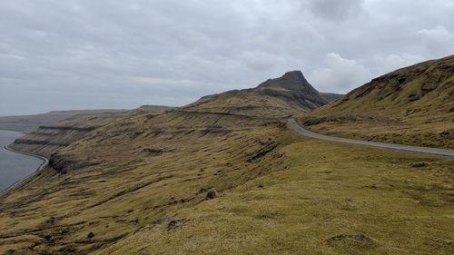 Scenic view of road by mountains against sky