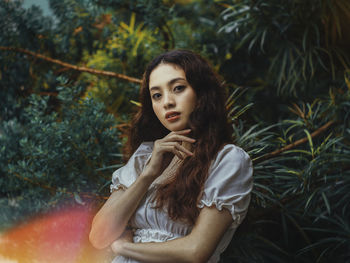 Portrait of young woman against plants