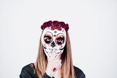 Portrait of young woman wearing mask against white background