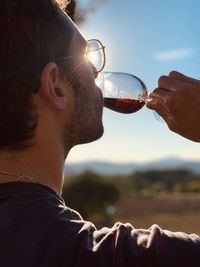 Man drinking wine against sky