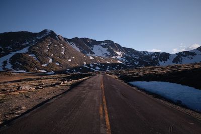 Road amidst snowcapped mountains against sky