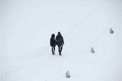 Rear view of people walking on snow covered land