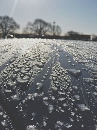 Close-up of wet glass against sky during rainy season