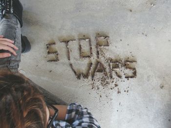 High angle view of woman sitting by text on floor