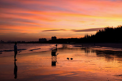 Silhouette man look at his happy family relax on beach with twilight sunset sky in cha-am