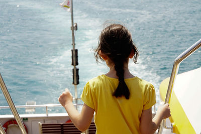 Rear view of girl standing on boat in sea