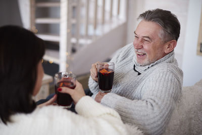 Happy mature couple with hot drinks in living room