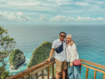 Rear view of woman standing by sea against sky