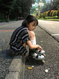 Cute little girl with roller skates outdoors sits on the ramp