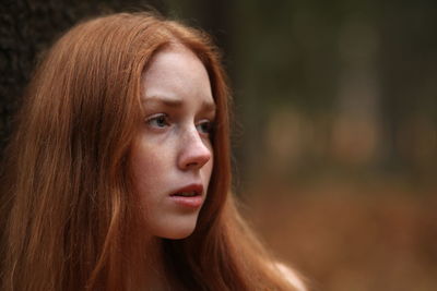 Close-up of thoughtful young woman with redhead looking away