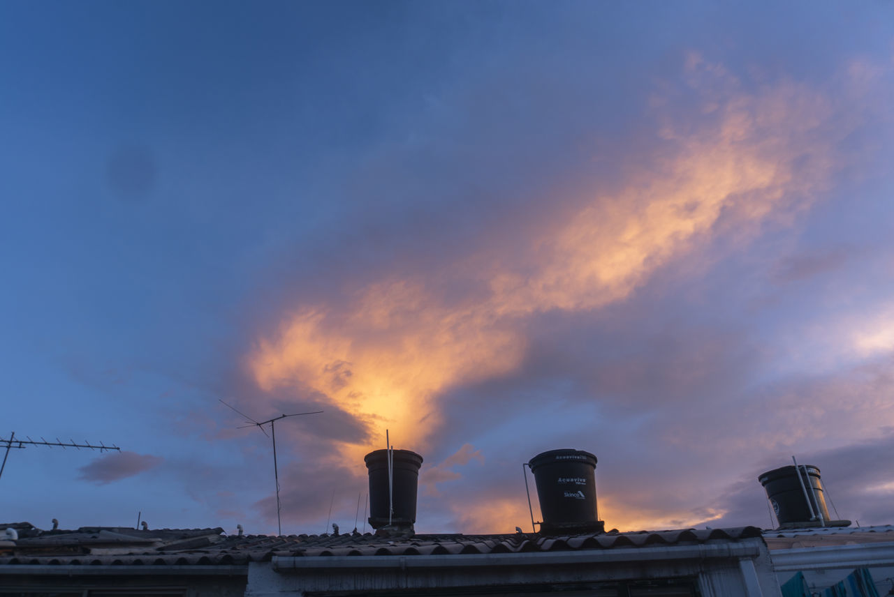 LOW ANGLE VIEW OF SMOKE STACKS AGAINST SKY DURING SUNSET