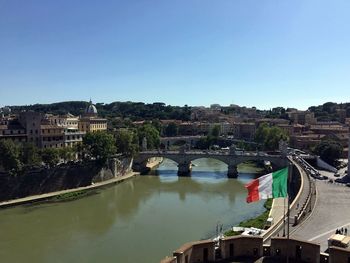 Scenic view of river by buildings against clear blue sky