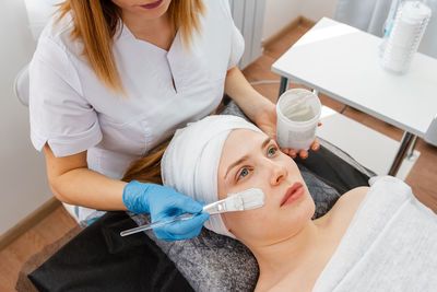 Hands of cosmetology specialist applying facial mask