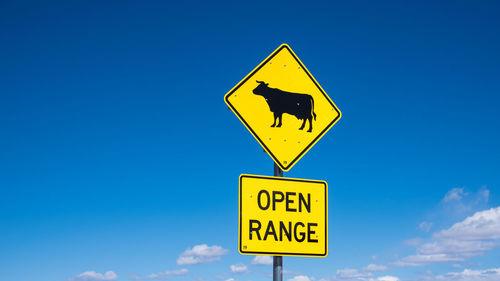 Low angle view of road sign against blue sky