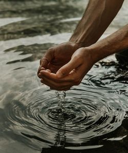 Close-up of hand holding water in lake