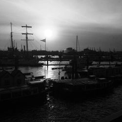 Boats moored at harbor in city against sky