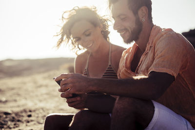 Mid adult couple using phone during sunny day