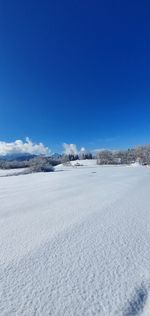 Scenic view of snow covered land against blue sky