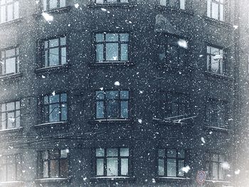 Reflection of building on snow covered glass window