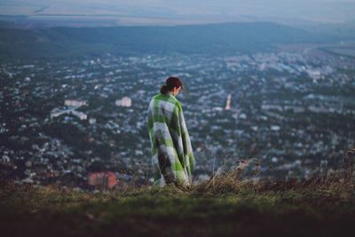 Woman standing on field by cityscape against sky