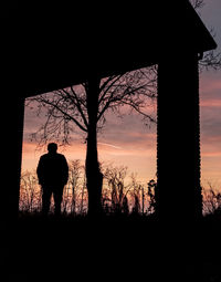Silhouette man standing on field against sky during sunset