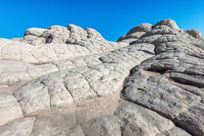 Low angle view of rock formations against clear blue sky