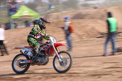 Motocross biker riding motorcycle on field