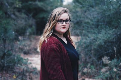 Young woman in eyeglasses standing in forest