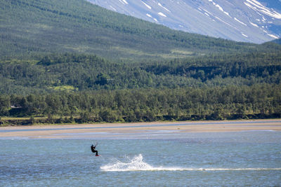 Person kitesurfing on lake against mountain