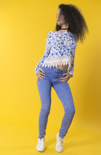 Young woman looking away against yellow background