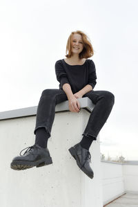 Portrait of young woman sitting against white background