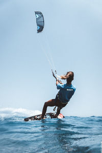 Man paragliding over sea against clear sky