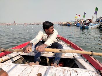 Young man sitting on boat against sea