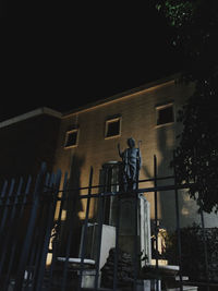 Low angle view of statue against building at night
