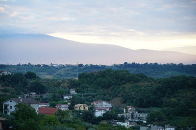 Houses in town by mountains against sky