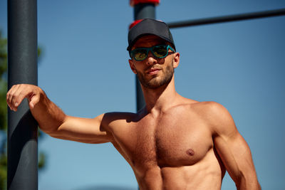 Portrait of shirtless man standing against sky