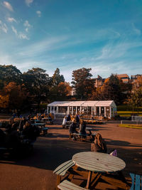 Rear view of people sitting at park against sky