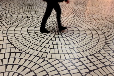 Low section of man walking on tiled floor